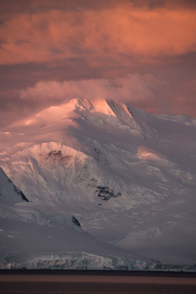 Colourful warm tones in a A vertical mountain range at sunset in Antarctica